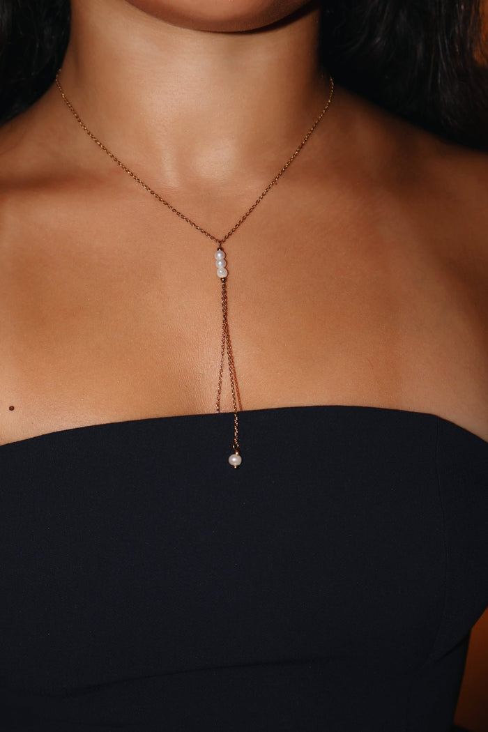 Gold pearl drop lariat Y necklace with freshwater pearls worn with a black strapless top