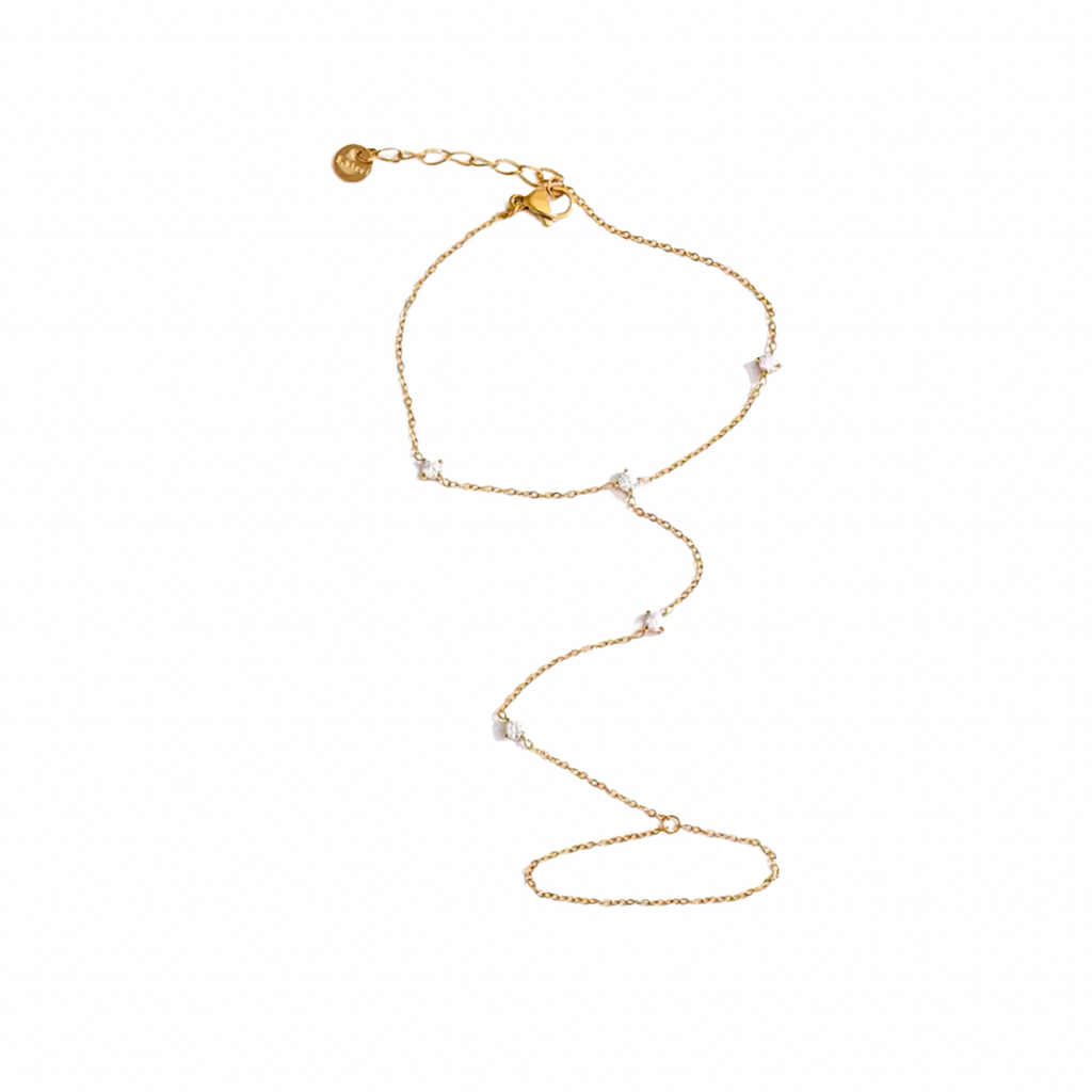 Gold hand chain with small beads on a white background