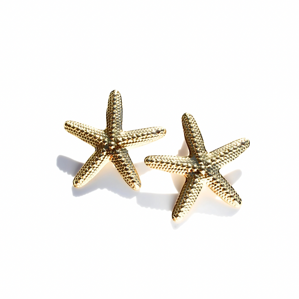 Gold starfish earrings on a white background