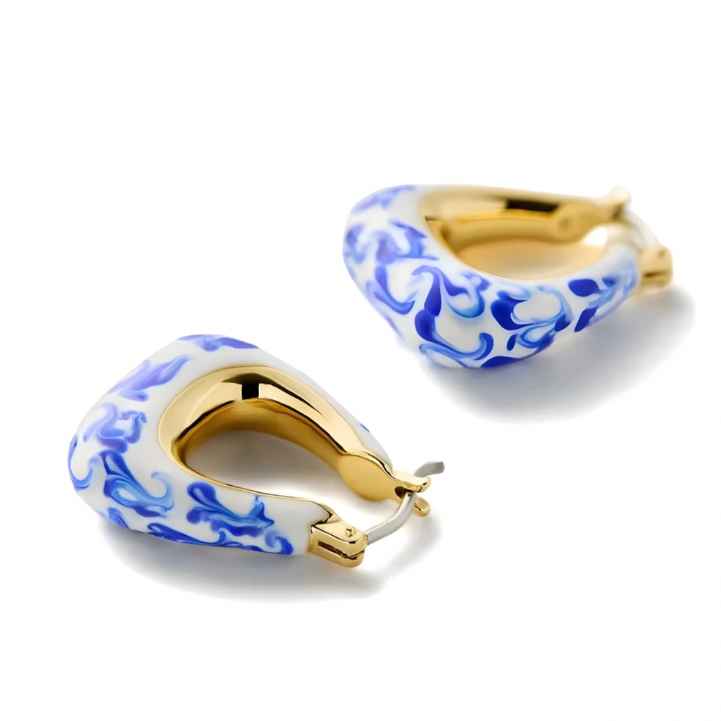 Pair of huggie earrings with blue pattern and gold accents on a white background