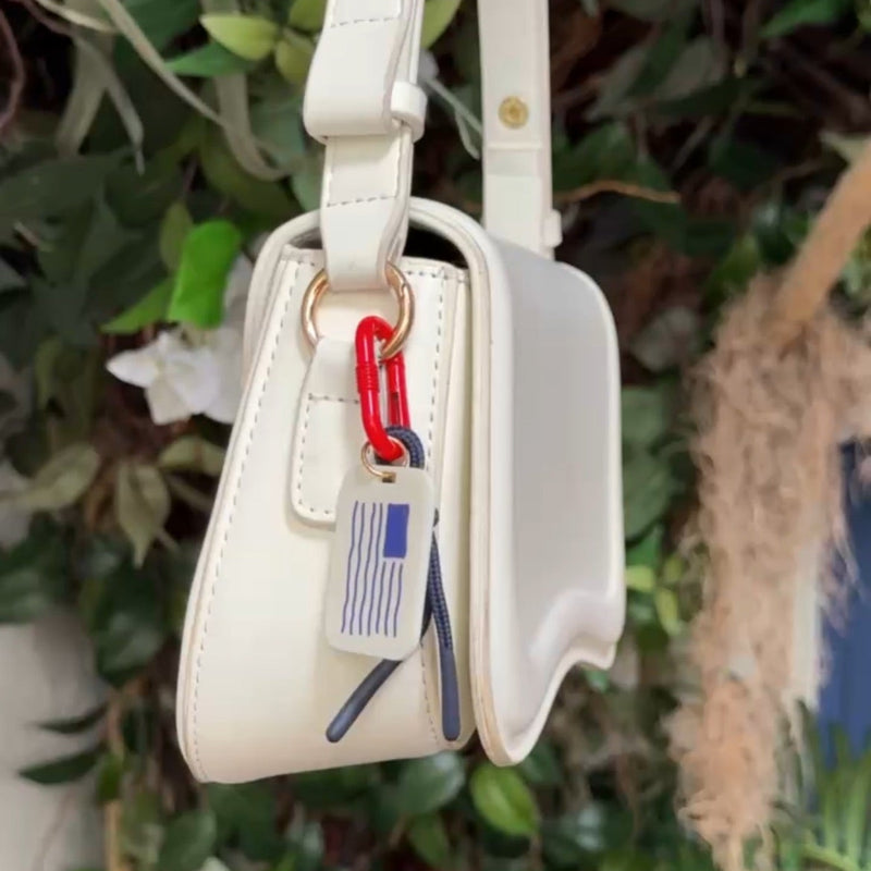 Navy and white striped flag acrylic carabiner bag charm clipped onto white handbag